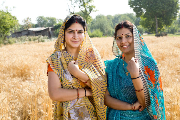 Portrait of two happy Indian woman standing in agricultural field